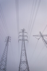  Towering electrical power pylons disappearing into thick fog portrait