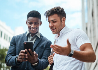 Poster - Business has never been smarter. Shot of two young businessmen using a smartphone together against an urban background.