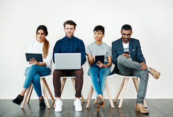 Poster - Enjoying instant notifications and endless apps. Shot of a group of young people using wireless technology while sitting in a row.