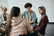 © Drazen - Young Muslim woman talks to group therapy members during their meeting at mental health center.