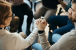 © Drazen - Close up of participants of mental health group therapy holding hands while sitting in circle.