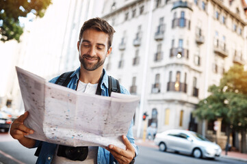 Wall Mural - Im exactly where I want to be. Cropped shot of a handsome young man looking at a map while touring a foreign city.