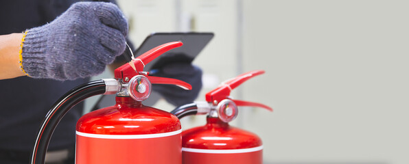 Fire extinguisher has hand engineer inspection checking pressure gauges to prepare fire equipment for protection and prevent emergency and safety rescue and alarm system training concept.