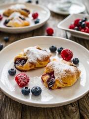 Wall Mural - Puff pastry with raspberries and blueberries on wooden table
