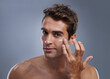 © Jeff Bergen/peopleimages.com - Even men like to be soft..... Studio shot of a handsome young man applying cream to his face.