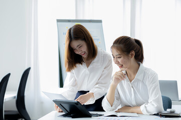 Atmosphere in the office of a startup company, two female employees are discussing, brainstorming ideas to working on summaries and marketing plans to increase sales and prepare reports to managers.