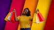Satisfied female showing shopping bags on multi-colored background, fashion