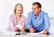 © Stigur/peopleimages.com - Mature man and wife calculating expenses using calculator. Portrait of a mature man and wife calculating monthly expenses using calculator.