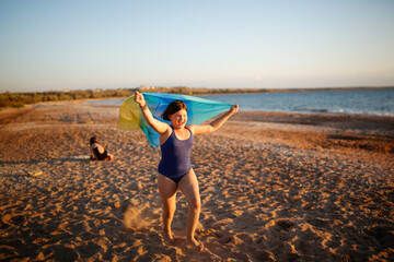 Wall Mural - Cute European children run along beach near sea with fluttering headscarf, happy childhood and freedom. Plus size kid, overweight. Children on beach at sunset in summer. Siblings run on sand together