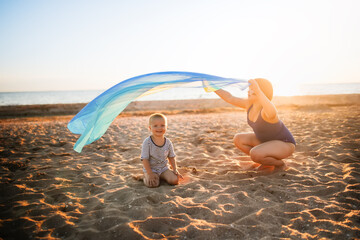 Wall Mural - Cute European children run along beach near sea with fluttering headscarf, happy childhood and freedom. Plus size kid, overweight. Children on beach at sunset in summer. Siblings run on sand together