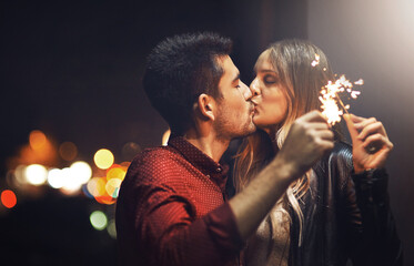 Sticker - The sparks fly when we kiss. Shot of a happy young couple celebrating with sparklers outside at night.