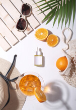 Flat Lay Of Vitamin C Skin Care Products. Summer Props Like Hat, Oranges, Palm Leaf, Goggles In The Background. Top View.