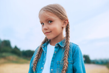 Wall Mural - Close-up portrait of funny little girl with pigtails outdoor in summer day. Summertime