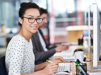 Poster - Make creativity a job. Shot of a young office worker sitting at her workstation in an office.