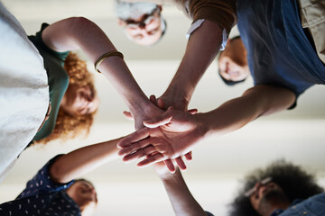 Poster - Lets get this project started. Low angle shot of a group of cheerful creative businesspeople forming a huddle with their hands inside of the office.