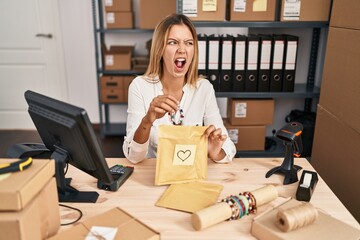 Sticker - Young blonde woman working at small business ecommerce angry and mad screaming frustrated and furious, shouting with anger. rage and aggressive concept.