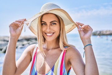 Poster - Young blonde girl smiling happy wearing swimsuit and summer hat at the beach.