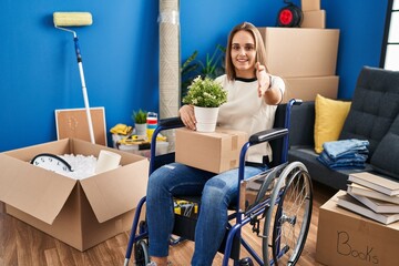 Poster - Young woman sitting on wheelchair moving to a new home smiling friendly offering handshake as greeting and welcoming. successful business.