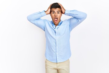 Sticker - Young hispanic man wearing business shirt standing over isolated background crazy and scared with hands on head, afraid and surprised of shock with open mouth