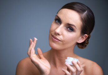 Wall Mural - Keeping her skin healthy. Portrait of an attractive young woman applying moisturizer to her skin.