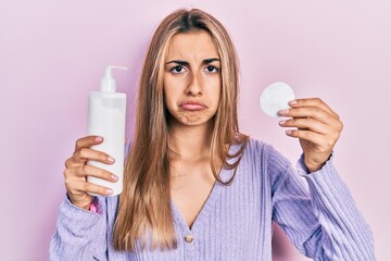 Poster - Beautiful hispanic woman holding cotton pad and make up remover depressed and worry for distress, crying angry and afraid. sad expression.