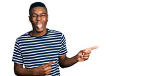 Young African American Man Pointing With Fingers To The Side Sticking Tongue Out Happy With Funny Expression.