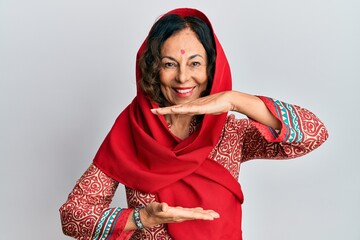 Sticker - Middle age hispanic woman wearing tradition sherwani saree clothes gesturing with hands showing big and large size sign, measure symbol. smiling looking at the camera. measuring concept.