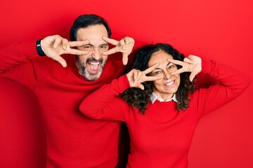 Sticker - Middle age couple of hispanic woman and man hugging and standing together doing peace symbol with fingers over face, smiling cheerful showing victory