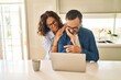 © Krakenimages.com - Middle age hispanic couple hugging each other using laptop at kitchen