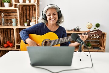 Canvas Print - Middle age grey-haired woman playing guitar working at radio studio.