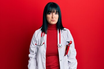 Poster - Young hispanic woman wearing doctor uniform and stethoscope depressed and worry for distress, crying angry and afraid. sad expression.