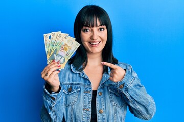 Poster - Young hispanic woman holding 50 romanian leu banknotes smiling happy pointing with hand and finger