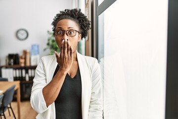 Wall Mural - African business woman working at the office covering mouth with hand, shocked and afraid for mistake. surprised expression