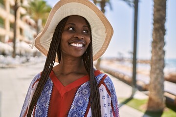 Young african american woman smiling happy wearing summer hat at the city.