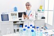 © Krakenimages.com - Middle age grey-haired woman wearing scientist uniform using smartphone at laboratory