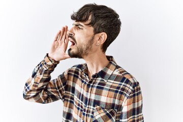 Sticker - Hispanic man with beard standing over isolated background shouting and screaming loud to side with hand on mouth. communication concept.