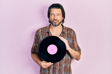 Poster - Middle age caucasian man holding vinyl disc looking at the camera blowing a kiss being lovely and sexy. love expression.