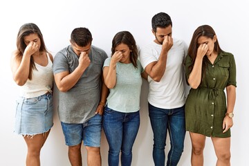 Canvas Print - Group of young hispanic friends standing together over isolated background tired rubbing nose and eyes feeling fatigue and headache. stress and frustration concept.