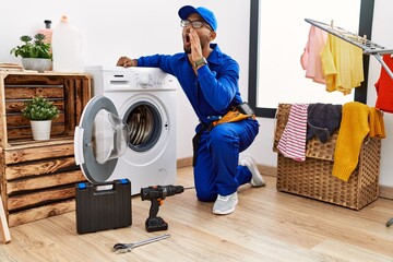 Wall Mural - Young indian technician working on washing machine shouting and screaming loud to side with hand on mouth. communication concept.