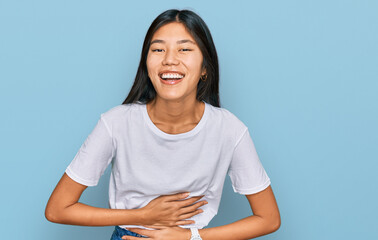 Sticker - Beautiful young asian woman wearing casual white t shirt smiling and laughing hard out loud because funny crazy joke with hands on body.