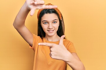 Sticker - Young brunette girl wearing casual orange t shirt smiling making frame with hands and fingers with happy face. creativity and photography concept.