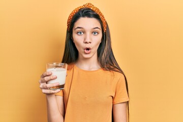 Sticker - Young brunette girl drinking a glass of milk scared and amazed with open mouth for surprise, disbelief face