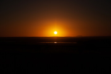 Wall Mural - Pristine golden sunset over farmland reflecting in water with mountains in the background