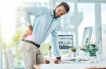 Poster - I need to work on my posture to prevent this pain. Shot of a young businessman suffering with back pain while working in an office.
