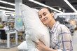 © puhimec - A young woman chooses a pillow in a home improvement store.