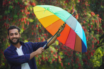 Wall Mural - Young man holding colorful umbrella smiling expression on face. simple and natural looking at the camera.