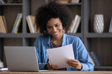 Satisfied happy African student girl receiving paper admission letter from school, university, college, reading document, smiling, laughing. Entrepreneur, businesswoman getting good deal, contract