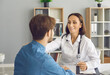 © Studio Romantic - Female doctor having conversation with young man who came to her office. Smiley woman in white lab coat with stethoscope talking to male patient, holding his shoulder, supporting and reassuring him