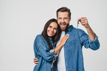 Homeowners. Happy Young Caucasian Couple Spouses Wife And Husband Holding Car House Flat Appartment Keys, Celebrating New Purchase Buying Real Estate Isolated In White Background. Mortgage Loan