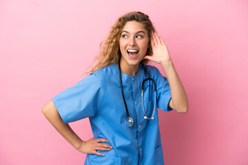 Wall Mural - Young surgeon doctor woman isolated on pink background listening to something by putting hand on the ear